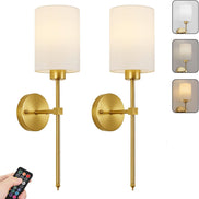 Pair of gold wall sconces with white lampshades and a remote control on a white background.